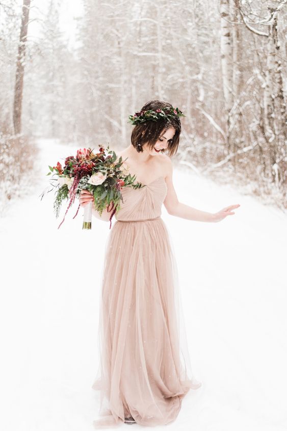 a simple and pretty blush strapless wedding dress with a draped bodice, a pleated skirt with a train and a greenery and burgundy bloom crown