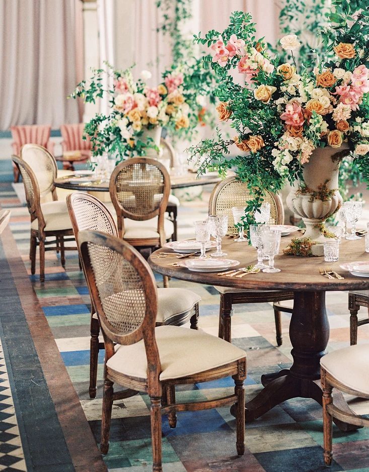 a chic wedding reception with round tables, oversized green and bright bloom centerpieces and refined crystal glasses
