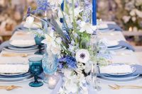 20 a lovely wedding tablescape with a periwinkle table runner, napkins and plates, bold blue candles and white and blue florals