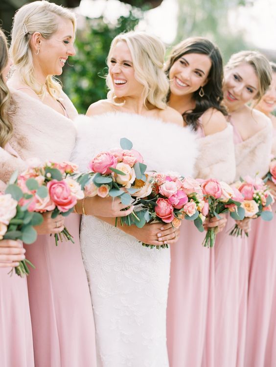 bridesmaids wearing pink maxi dresses and matching blush cover ups and holding cool pink and blush peony rose wedding bouquets