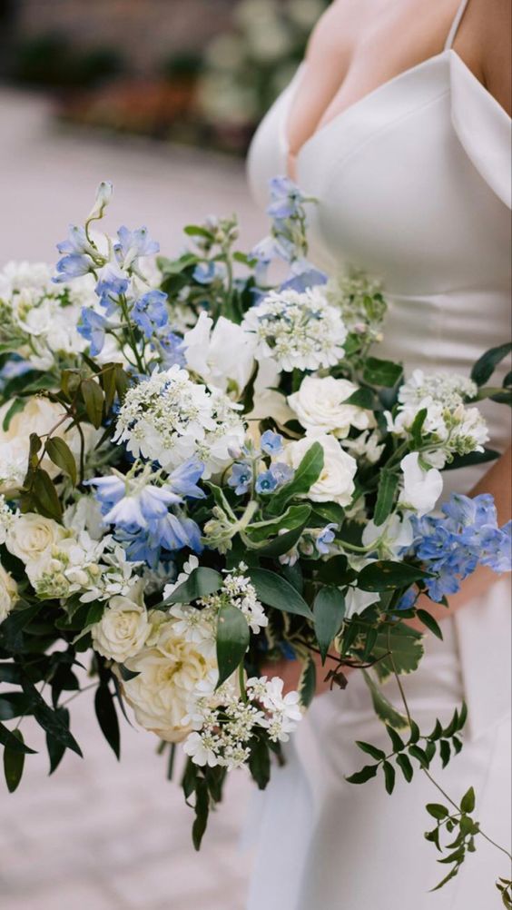 a lush wedding bouquet of neutral and periwinkle blooms and cascading greenery is a refined and chic idea for your wedding