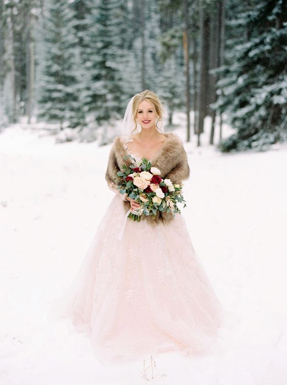 an exquisite bridal look with a blush wedding ballgown, a neutral faux fur shawl, a veil and a bold lip is classics for winter