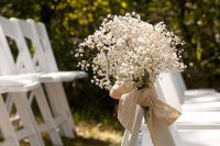 22 white chairs accented with baby’s breath and burlap bows to style your wedding aisle in a very chic and glam way