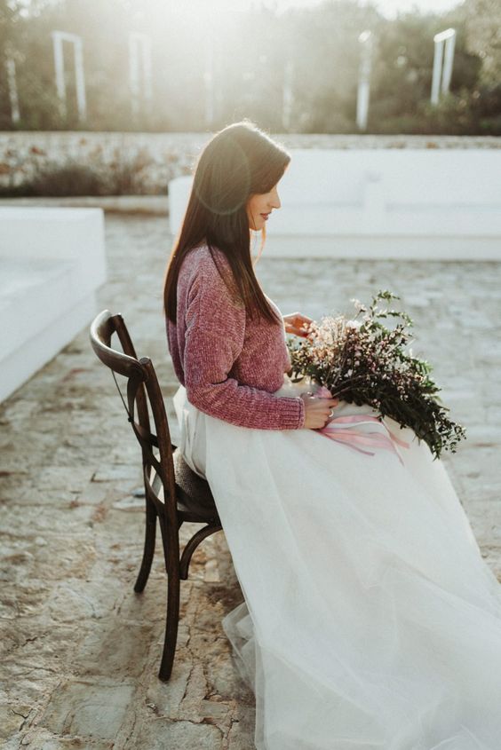 a winter bride wearing a white layered skirt, a pink sweater and with an airy and dreamy wedding bouquet with pink ribbons