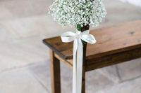 23 a wooden bench in the wedding aisle accented with a white bow with a baby’s breath arrangement looks amazingly chic