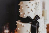 24 a white pearl wedding cake with black bow and ribbons is a chic and glam idea for a black and white wedding in modenr style