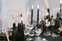 25 a beautiful black and white wedding tablescape with a black tablecloth and white napkins, black vases and candles, dried blooms and grass