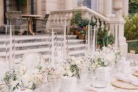 25 a super refined neutral wedding tablescape with neutral and pastel blooms, gold-rimmed glasses, tall and thin candles and gold print chargers