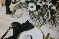 26 a chic modern black and white wedding tablescape with a white anemone centerpiece with greenery, a black napkin and a card with a tassel