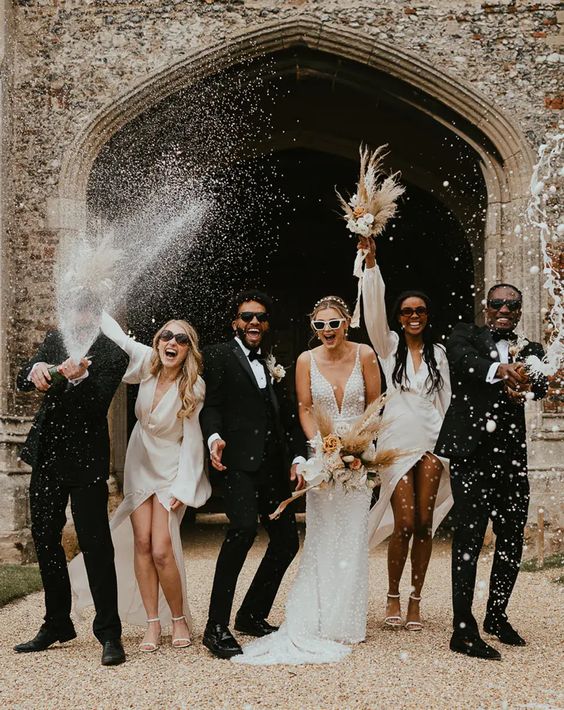 the couple and their friends wearing white and black and white outfits and rocking white dried bloom bouquets for a modern wedding