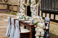 28 a refined Bridgerton wedding tablescape with tall candelabras decorated with super lush florals, blue and blush glasses, elegant porcelain and pastel blue chair covers