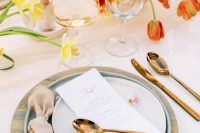 29 a lovely Bridgerton-inspired wedding tablescape with bold tulips, pastel candles, printed chargers and blue plates and elegant cutlery