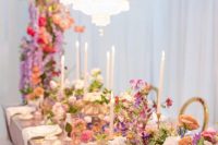 30 a jaw-dropping Bridgerton wedding tablescape with super lush pastel and bright florals on the table and over it, with tall and thin candles and delicate porcelain