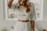 31 a minimalist bridal look with a plain crop top with short sleeves and high waisted pants with a sash, statement earrings and some more jewelry