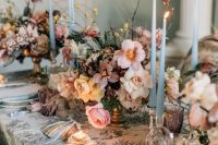 32 a fantastic wedding tablescape with a printed tablecloth, lush blush, peachy and mauve blooms, thin and tall blue candles and napkins