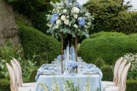 32 a refined and beautiful blue Bridgerton wedding reception space with lush florals and greenery and serenity linens