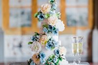 34 a beautiful wedding cake decorated with natural and sugar blooms in peachy and blue plus greenery for a Bridgerton wedding
