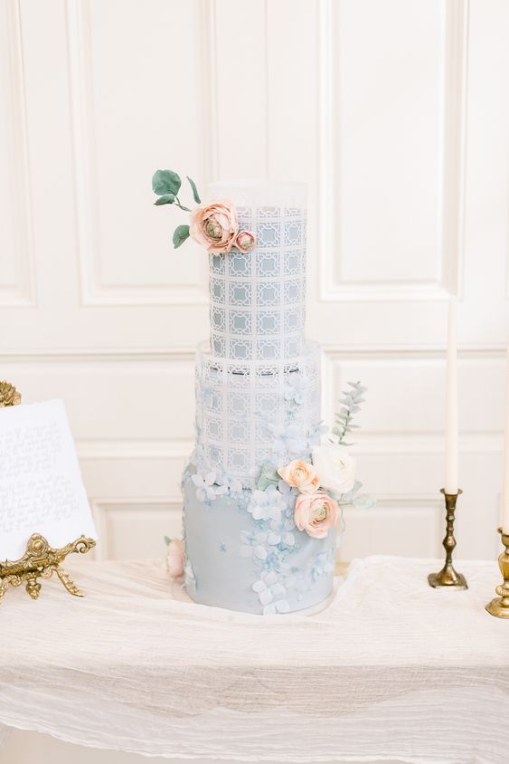 a dusty blue Bridgerton wedding cake with beautiful patterns and textural sugar blooms plus natural ones on top