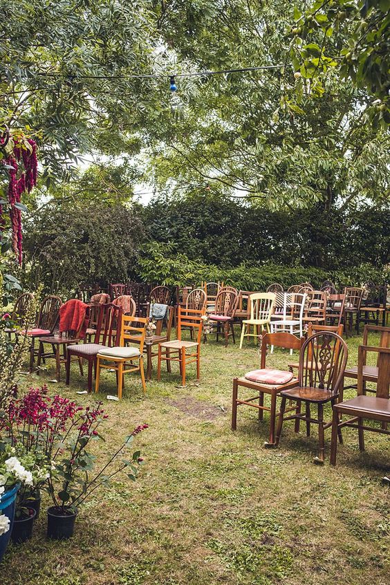 a lovely and cozy back garden wedding ceremony space with mismatching chairs, bright blooms and lots of greenery