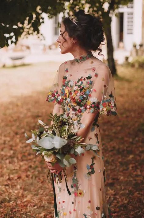 a cool sheath wedding dress with colorful floral embroidery, a high neckline and short sleeves for a bloom-loving bride