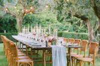 37 a beautiful garden wedding reception space with string lights, trestle tables, woven chairs and pastel linens
