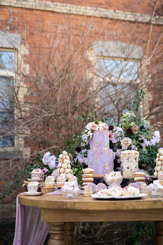 a gorgeous and refined wedding sweets table with a textural lilac and floral wedding cake, a couple of croquembouches, cupcakes and other delicious desserts