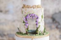 38 a jaw-dropping Bridgerton wedding cake with an edible wedding arch integrated and some natural blooms on top