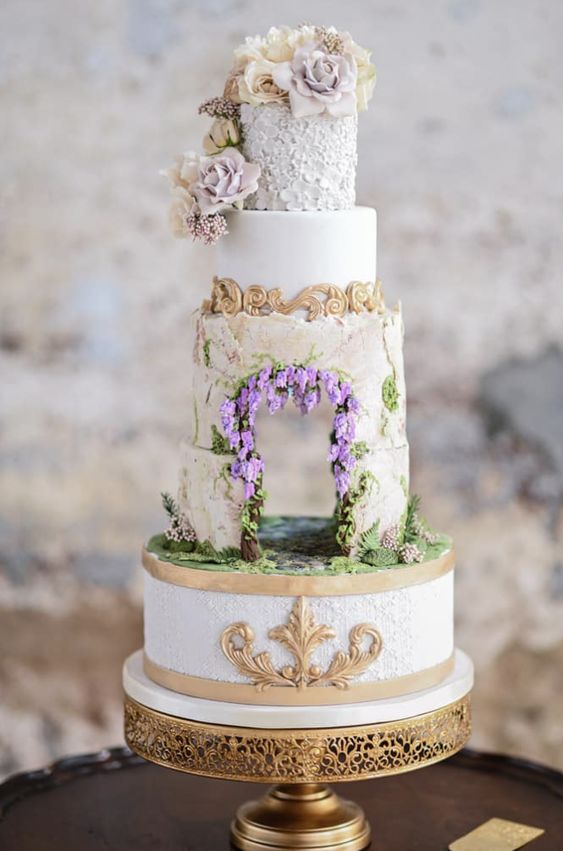 a jaw-dropping Bridgerton wedding cake with an edible wedding arch integrated and some natural blooms on top
