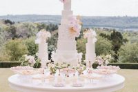 39 a jaw-dropping wedding dessert table with an assortment of neutral wedding cakes topped with pastel and gilded blooms, macarons, souffle and other sweets