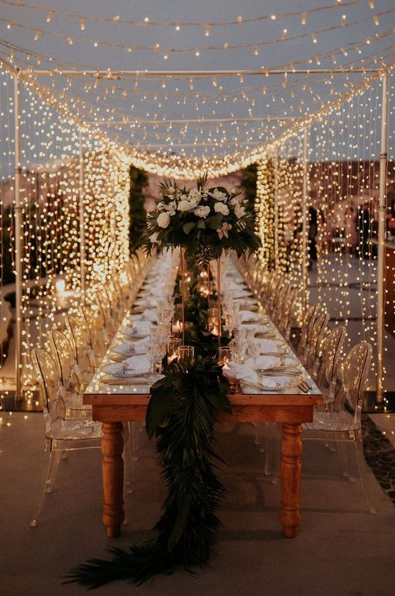 a fantastic outdoor wedding reception with a vintage table, clear acrylic chairs and a light canopy over the table