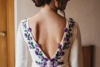 41 a wedding dress featuring purple and lilac embroidered flowers and leaves, a cutout back on buttons and a long train