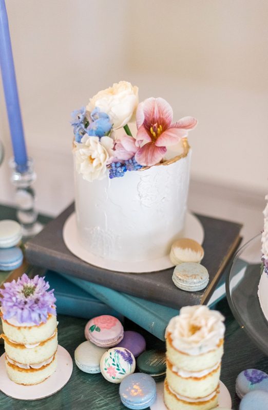 refined and delicate wedding sweets - mini cakes and a large textural white one, all topped with fresh blooms