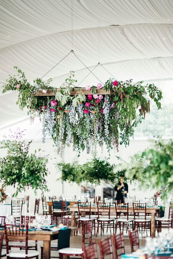 a beautiful and chic hanging floral decoration with greenery over the reception can substitute usual centerpieces