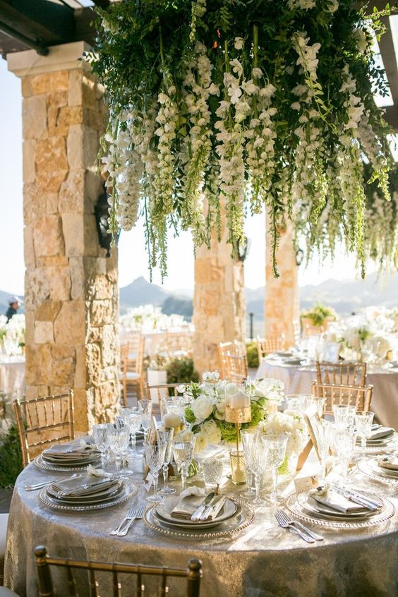 a refined neutral wedding tablescape with a lush hanging floral chandelier with greenery over it to make a bold statement