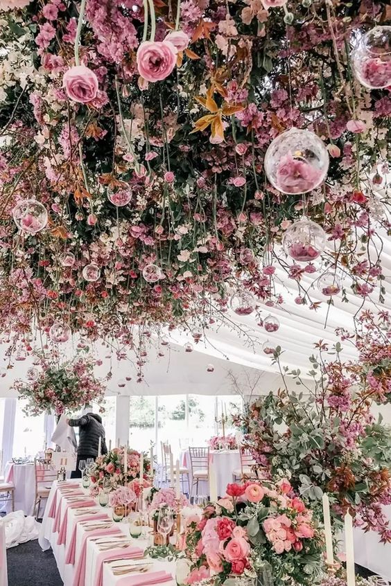 a jaw-dropping wedding reception space fully done with pink and coral florals all over including overhead hanging installations is wow
