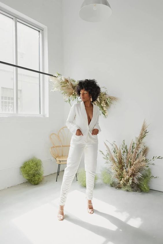 a killer bridal pantsuit with a deep neckline and fitting pants, white shoes and statement earrings
