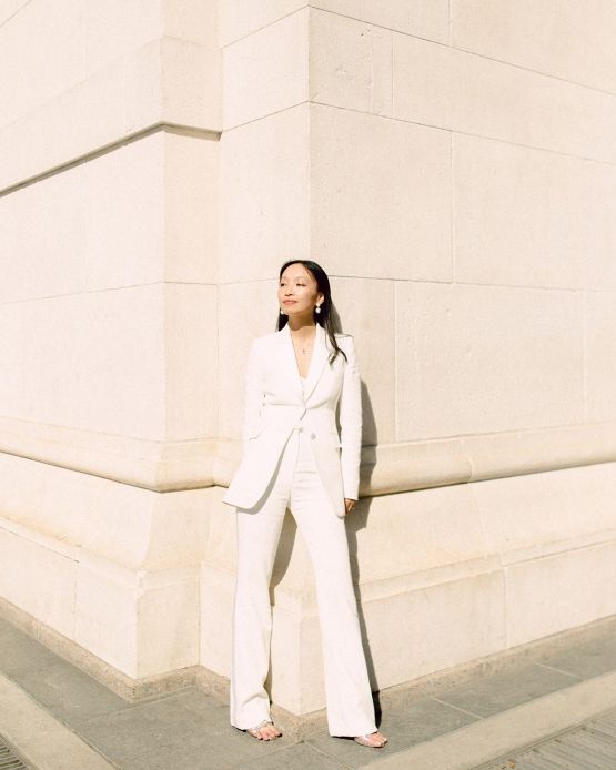 a chic bridal pantsuit with a top, a long blazer, flare pants and statement earrings for ultimate elegance
