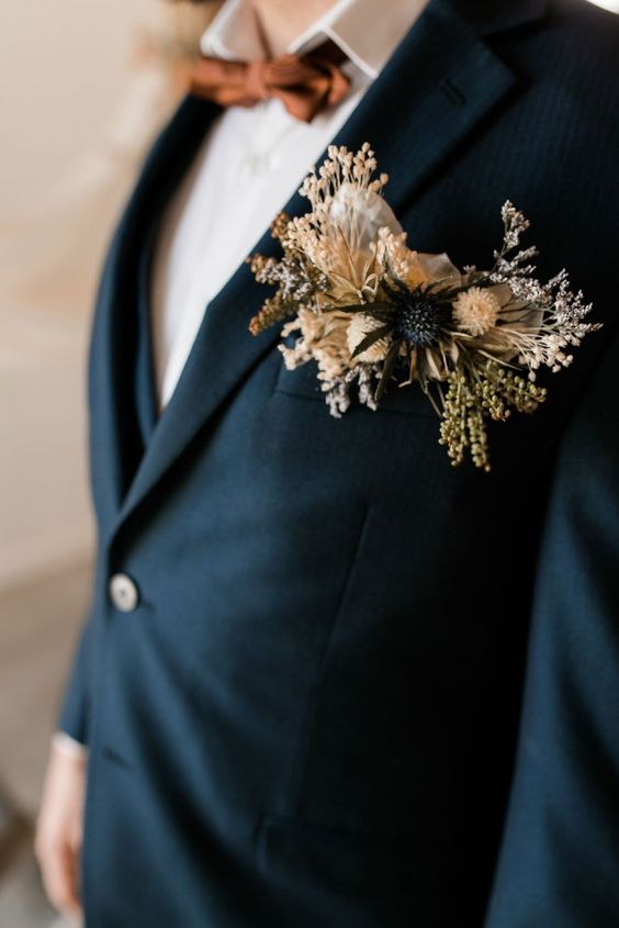 a black blazer with a floral pocket square styled with dried blooms and grass, a thistle is a pretty idea for a boho groom