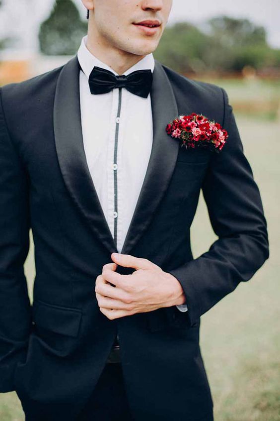 a black tux with silk lapels and a bold red pocket square with pink and red blooms that brings a touch of color
