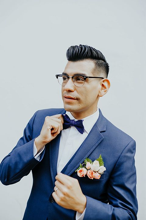 a bold blue suit with a cobalt blue bow tie and a fresh pocket square decorated with white and peachy blooms and leaves for a contrast