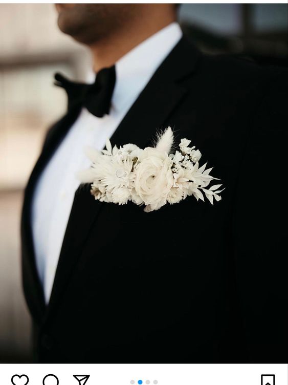 a classic black tux with a contrasting pocket square done with white dried blooms and grasses for a super elegant and modern feel