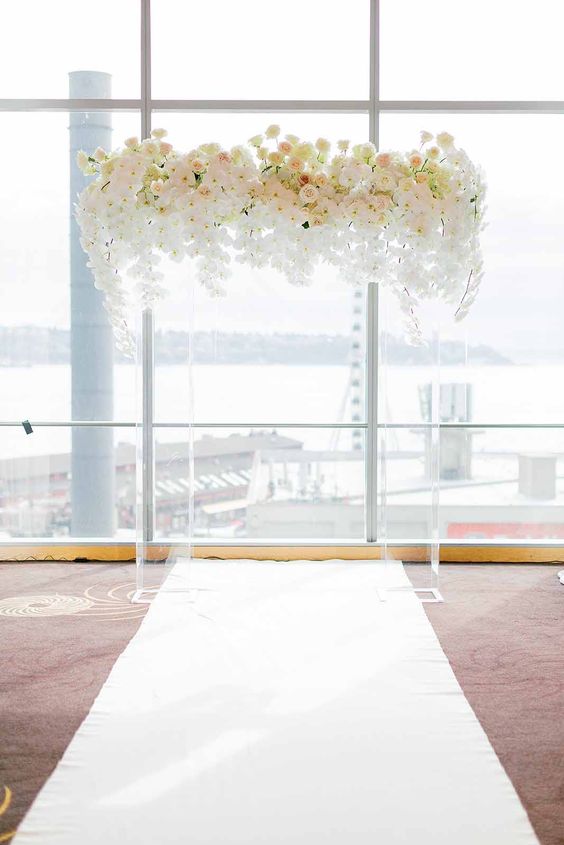 a clear lucite wedding arch topped with blush and white blooms with an ombre effect is a gorgeous and fresh solution for a modern luxurious wedding