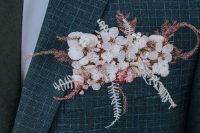 a grey and blue plaid print blazer styled with white and pink blooms, dried leaves and grasses that is a stylish and delicate accent