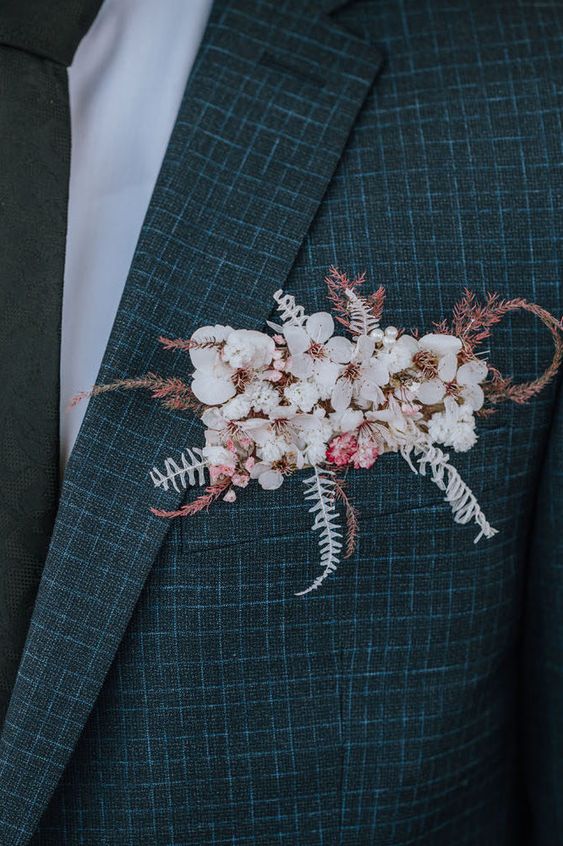a grey and blue plaid print blazer styled with white and pink blooms, dried leaves and grasses that is a stylish and delicate accent