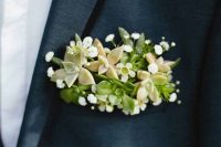 a grey blazer with black rim lapels and a fresh boutonniere done with white and green blooms and succulents for a fresh look