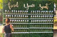 a large boxwood champagne wall as a seating chart, with gold calligraphy and seatign cards is chic and cool