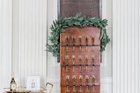 a small and chic wedding champagne copper wall with metal holders and a greenery garland on top is a bold solution