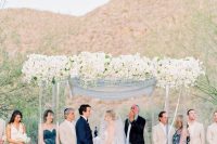 a sophisticated lucite wedding arbor with blue cutrains and lush white blooms on top plus matching arrangements on each side