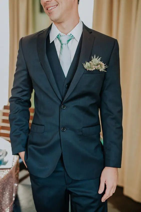 a stylish grey three-piece suit and a pocket square accented with thistles and waxflower for a whimsical and fresh touch in the look