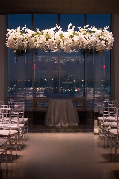 a super modern clear lucite wedding arbow topped with white orchids and greenery is a timelessly luxurious and modern idea